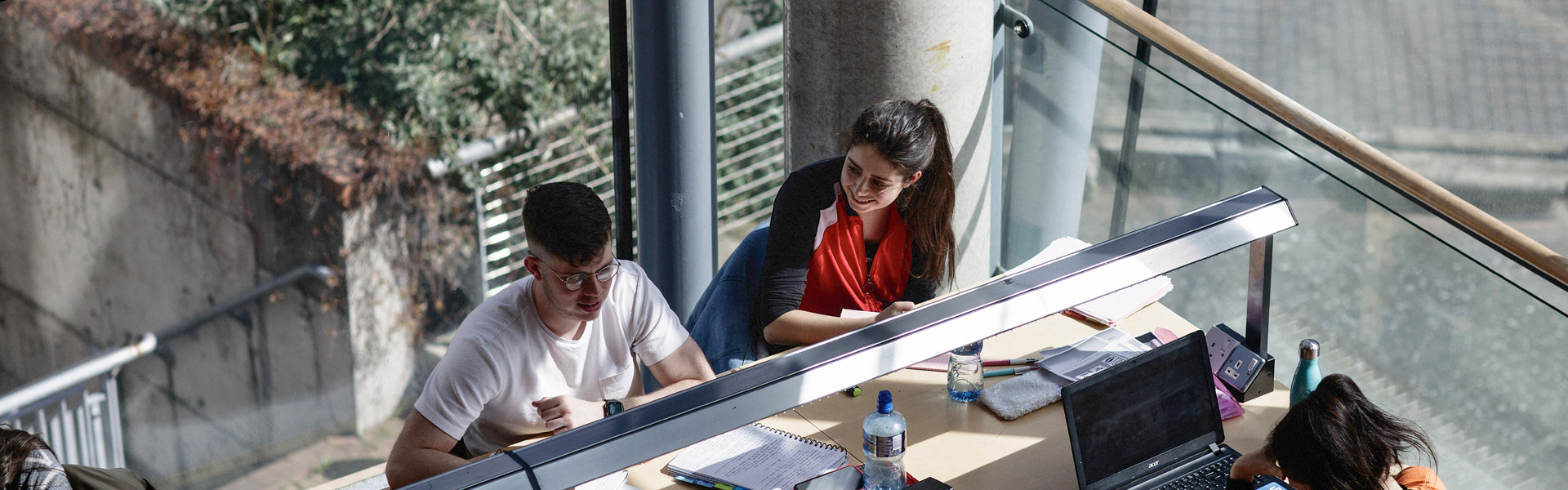 Students studying at a desk in a library on campus