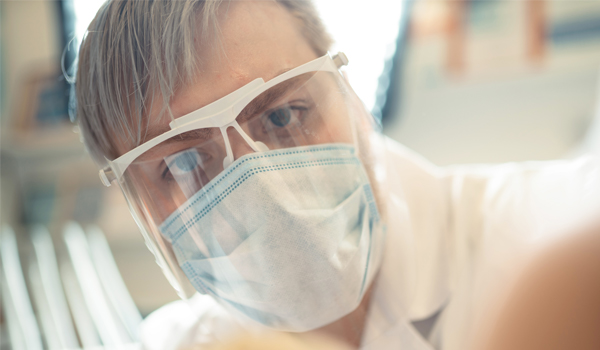 man wearing goggles, mask and lab coat